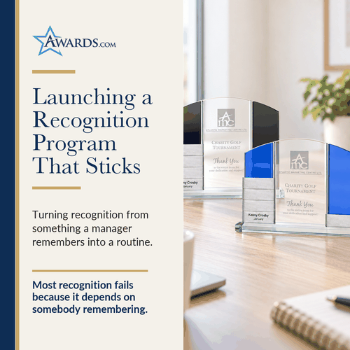 Glass awards with stacked silver name plates on an office desk